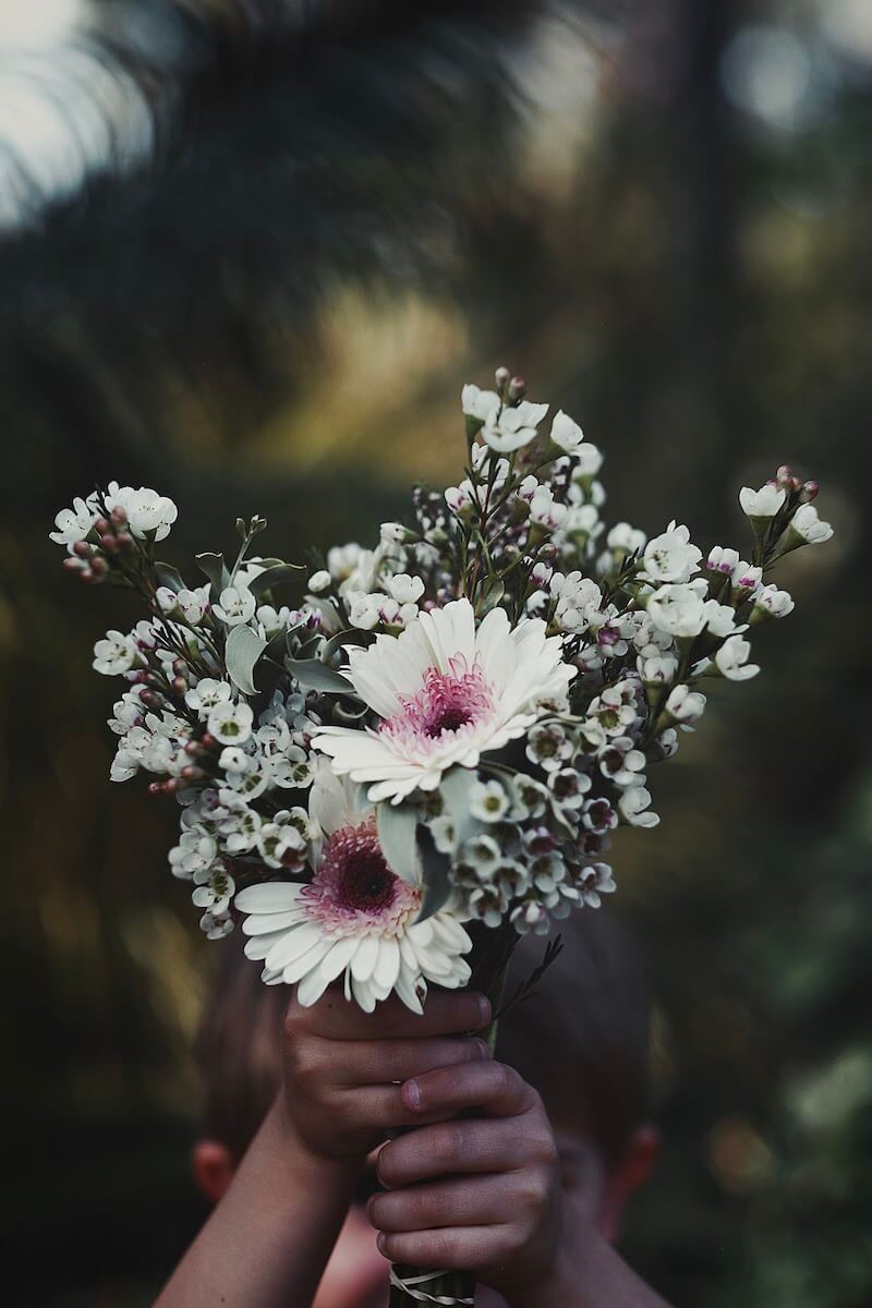 Child holding a white bouquet of flowers.